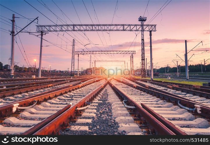 Modern railway station at night in Europe. Industrial landscape with railroad junction, colorful sky at sunset. Railway platform in twilight. Railway background. Heavy industry. Freight transportation