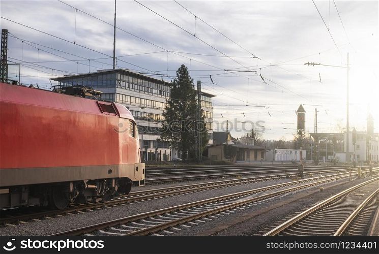 Modern red locomotive traveling on railway tracks. Public transport. Train travel concept. High-speed locomotive near Singen train station, Germany.