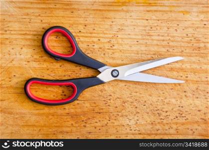 Modern scissors sit atop a wooden board