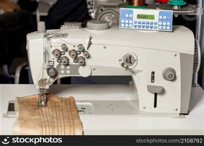 Modern sewing machine for sewing clothes with programmable mechanisms and forms of thread tension. Close-up, high resolution.. Professional programmable sewing machine for hemming and sewing clothes. Close-up.