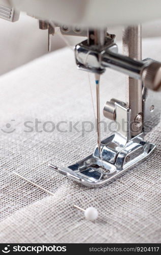 Modern sewing machine presser foot with linen fabric and thread, closeup. Sewing process clothes, curtains, upholstery. Business, hobby, handmade, zero waste, recycling, repair concept