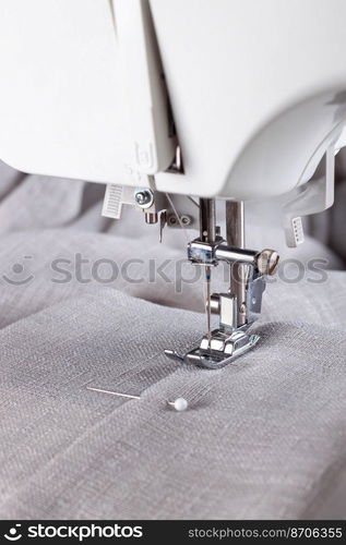 Modern sewing machine presser foot with linen fabric and thread, closeup, copy space. Sewing process clothes, curtains, upholstery. Business, hobby, handmade, zero waste, recycling, repair concept