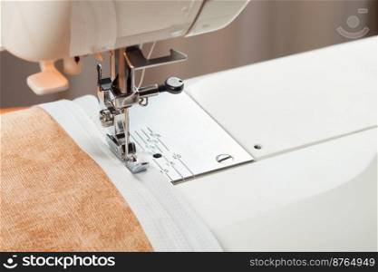 Modern sewing machine sews on the zipper on beige item of clothing. sewing process. modern sewing machine presser foot and zipper