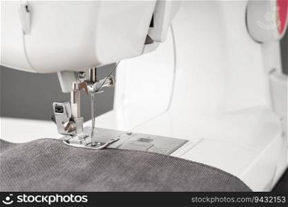 Modern sewing machine with gray fabric and. Sewing process clothes, curtains, upholstery. Business, hobby, handmade, zero waste, recycling, repair concept