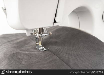 Modern sewing machine with gray fabric and. Sewing process clothes, curtains, upholstery. Business, hobby, handmade, zero waste, recycling, repair concept