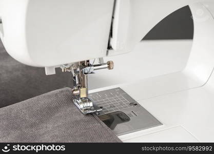 Modern sewing machine with gray fabric. Sewing process clothes, curtains upholstery. Business, hobby, handmade, zero waste, recycling, repair concept