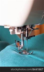 Modern sewing machine working with turquoise fabric. Sewing process.. Modern sewing machine and turquoise fabric