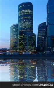 Modern skyscrapers at night on river bank
