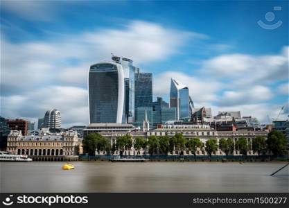 Modern skyscrapers of The City of London as seen from the South shore of the river Thames on a cloudy Summer day. Long exposure.
