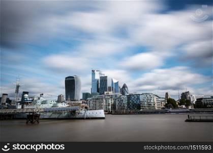 Modern skyscrapers of The City of London as seen from the South shore of the river Thames on a cloudy Summer day. Long exposure.