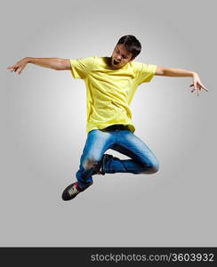 Modern slim hip-hop style man jumping dancing on a grey background