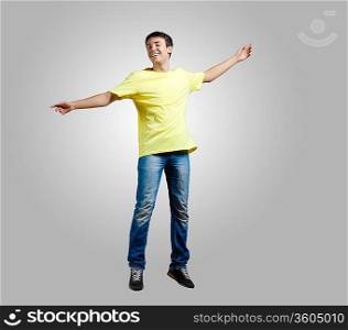 Modern slim hip-hop style man jumping dancing on a grey background