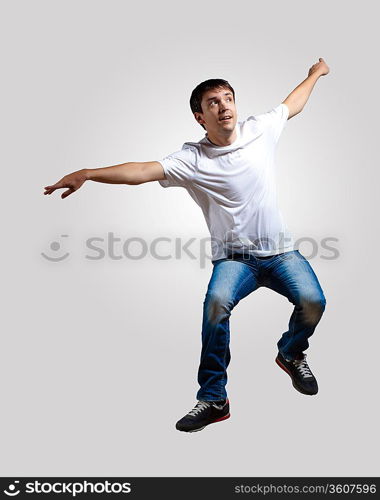 Modern slim hip-hop style man jumping dancing on a grey background
