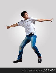 Modern slim hip-hop style man jumping dancing on a grey background