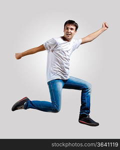 Modern slim hip-hop style man jumping dancing on a grey background