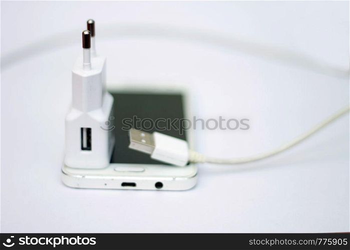 Modern smartphone and phone charge with power cord isolated on the white bckground