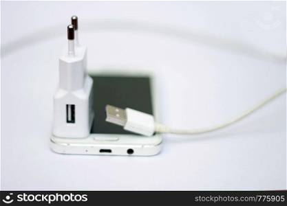 Modern smartphone and phone charge with power cord isolated on the white bckground