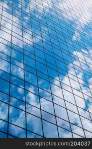 Modern smoked glass office building against a blue cloudy sky.. Office in the sky