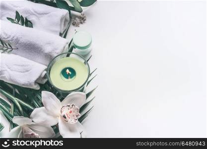 Modern spa background with white towels, tools and green herbs, orchid flowers, candle equipment, top view, place for your design. Wellness treatment , skin and body care concept