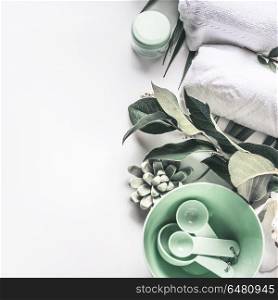 Modern spa background with white towels, tools and green herbs, top view, place for your design. Wellness treatment , skin and body care concept