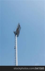 Modern spotlight pole under the clear blue sky which located in the football stadium.