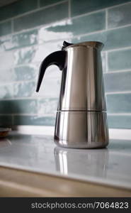 Modern stainless geyser coffee macker on kitchen on the induction panel on blue tiles background.. stainless geyser coffee maker on a background of blue tiles