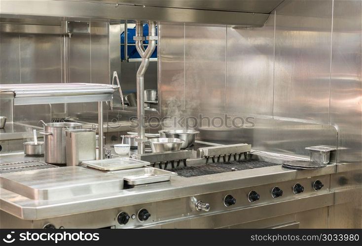 Modern stainless steel hobs in commercial kitchen. Food being cooked in commercial stainless steel kitchen in restaurant. Modern stainless steel hobs in commercial kitchen