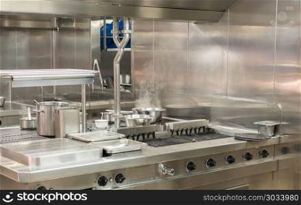 Modern stainless steel hobs in commercial kitchen. Food being cooked in commercial stainless steel kitchen in restaurant. Modern stainless steel hobs in commercial kitchen