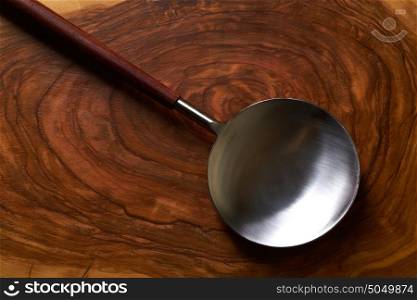 Modern stainless steel spoon spatula on wooden olive board