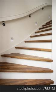 Modern steel staircase with wooden steps in a new apartment in a residential building with spots light in wall close-up. Modern steel staircase with wooden steps in a new apartment in a residential building with spots light in wall