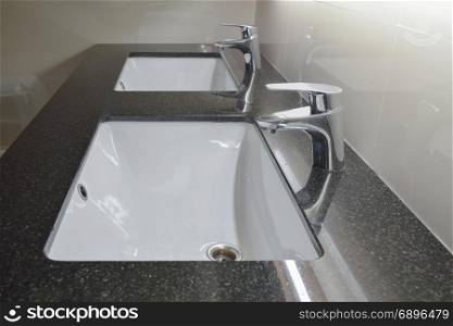 Modern style faucet with under counter wash basin in restroom