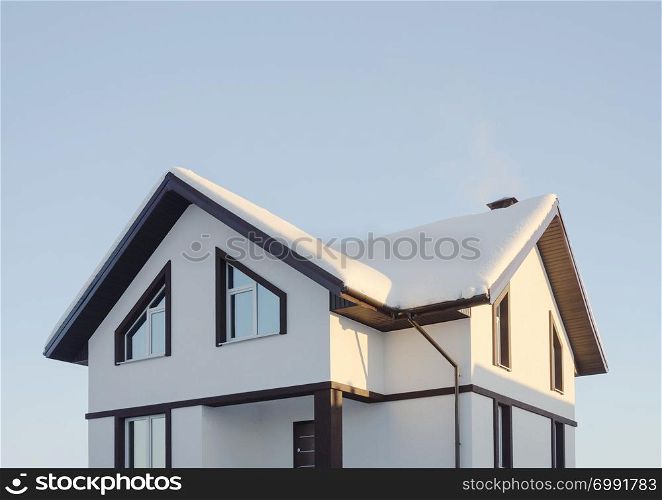 Modern suburban cottage covered with snow, sunny winter day