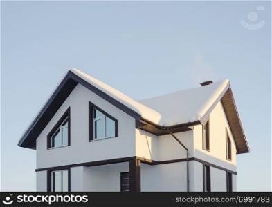 Modern suburban cottage covered with snow, sunny winter day