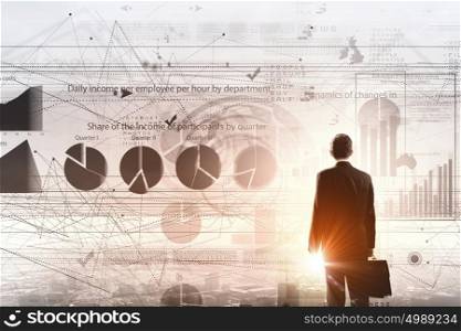 Modern technologies in business. Rear view of businessman with suitcase and diagrams on virtual panel