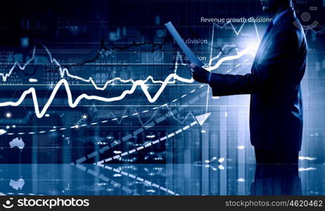 Modern technologies in business. Side view of businessman with papers in hand and diagrams on virtual panel
