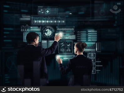 Modern technologies in use. Rear view of businessman and businesswoman working with virtual panel interface