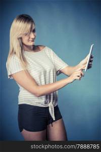 Modern technologies leisure and lifestyle concept. Blonde woman casual style girl with computer tablet on blue vintage filter