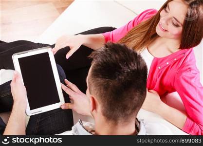 modern technologies leisure and relationships concept. Young couple using pc computer tablet sitting on couch at home websurfing on internet, high angle view