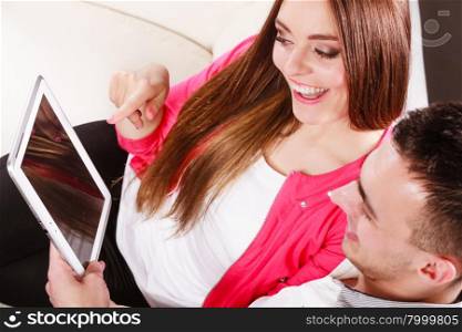 modern technologies leisure and relationships concept. Young couple using pc computer tablet sitting on couch at home websurfing on internet, high angle view