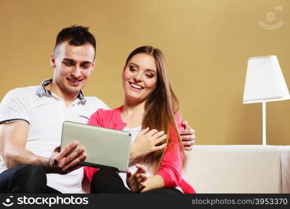 modern technologies leisure and relationships concept. Young couple with pc computer tablet sitting on couch at home websurfing on internet