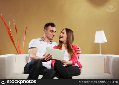 modern technologies leisure and relationships concept. Young couple with pc computer tablet sitting on couch at home websurfing on internet