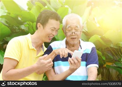 Modern technology, age and people concept. Asian family using smart-phone. Family living lifestyle at garden.
