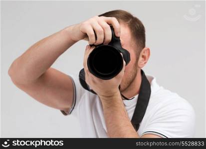 modern technology and people concept - male photographer taking picture with digital camera