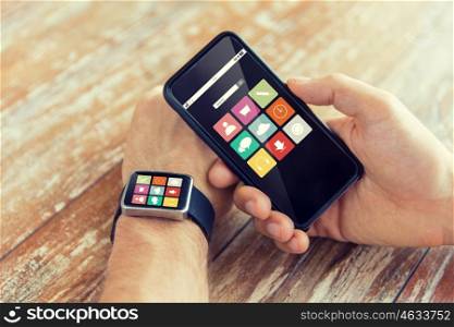 modern technology, application and people concept - close up of male hand holding smart phone and wearing watch with app icons on screen at home