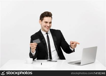 Modern technology, business, career, e-commerce and online trading concept: Caucasian businessman holding credit card in one had and pointing on laptop with other hand. Modern technology, business, career, e-commerce and online trading concept: Caucasian businessman holding credit card in one had and pointing on laptop with other hand.