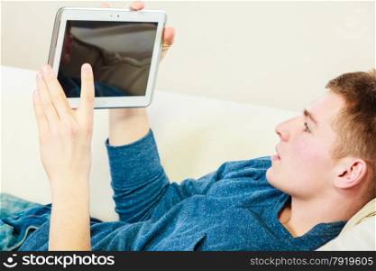 Modern technology home and relaxation concept. Young man with pc computer digital tablet on couch