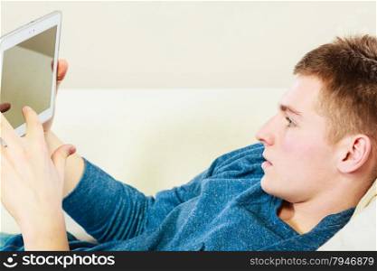 Modern technology home and relaxation concept. Young man with pc computer digital tablet on couch