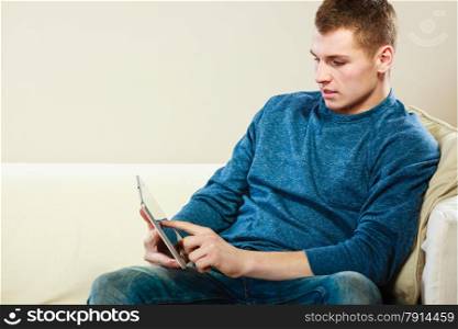Modern technology leisure and relaxation concept. Young man with pc computer digital tablet on couch