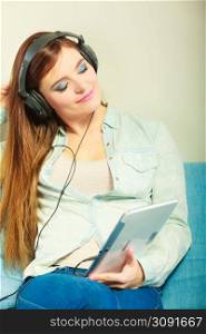 Modern technology leisure concept. Young attractive woman with headphones closed eyes relaxing using tablet