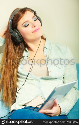 Modern technology leisure concept. Young attractive woman with headphones closed eyes relaxing using tablet